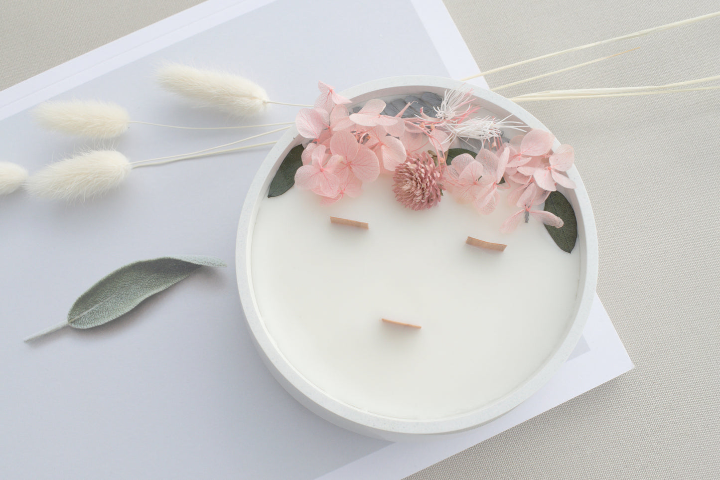 Handgemachte Kerze mit getrockneten Blüten im Betongefäß und Holzdocht, skandinavische Deko und Geschenkidee