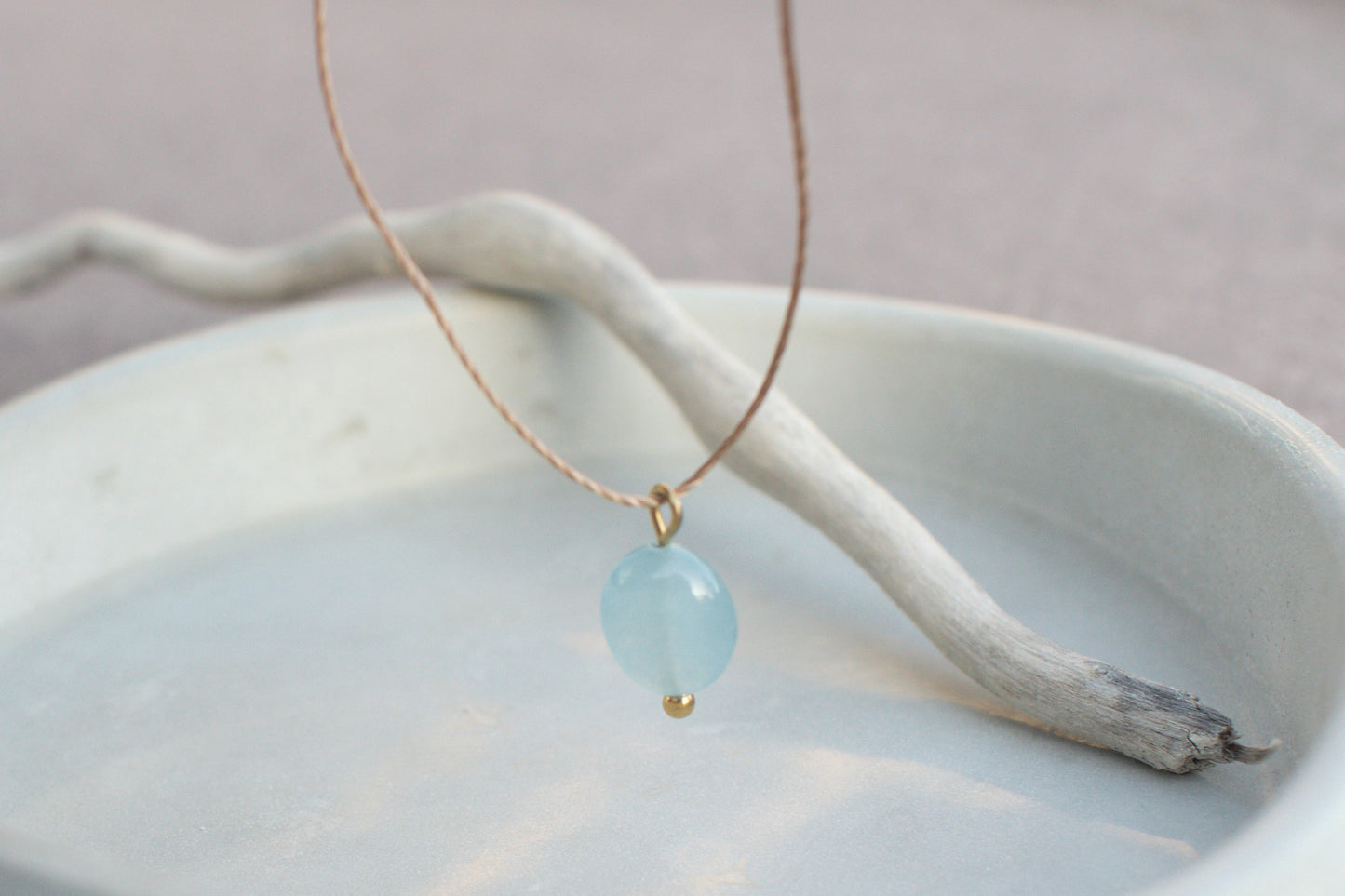 Minimalist necklace with blue, flat aquamarine gemstone on a brown nylon cord