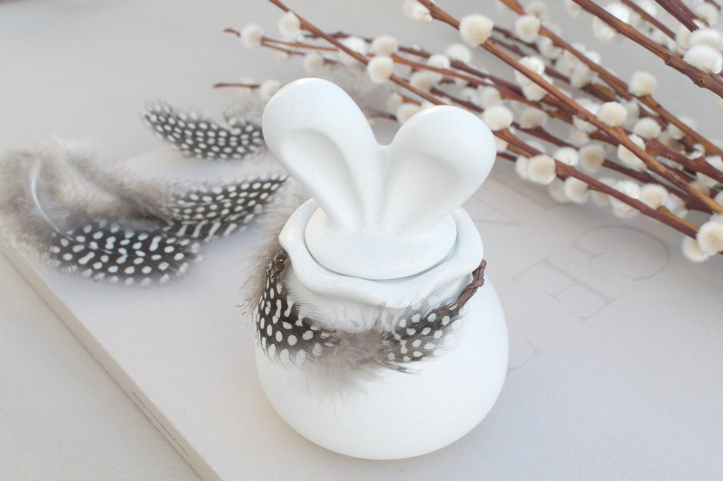 Osterdeko Skandi – Dose aus weißem Beton mit Hasenohren & Perlhuhn-Federn