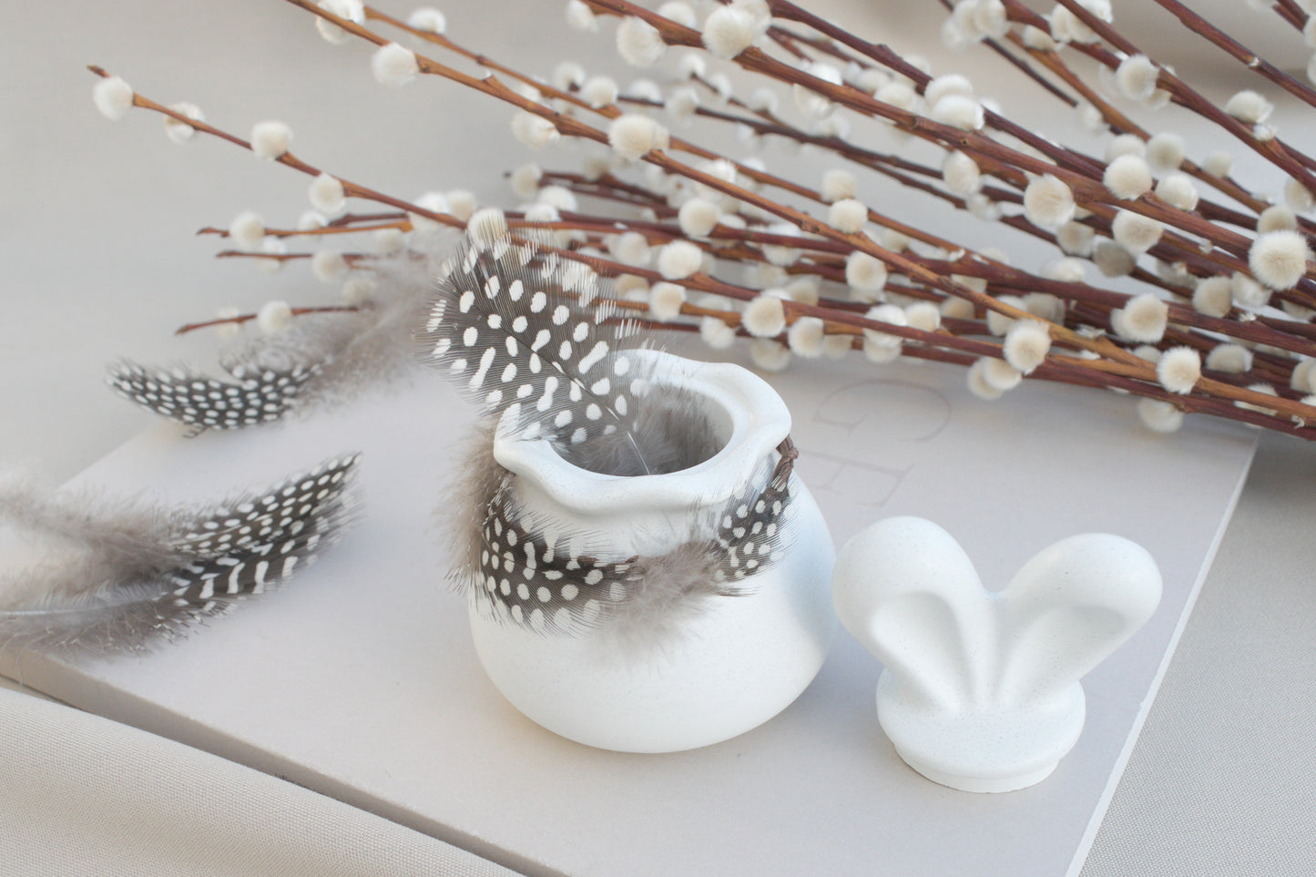 Osterdeko Skandi – Dose aus weißem Beton mit Hasenohren & Perlhuhn-Federn