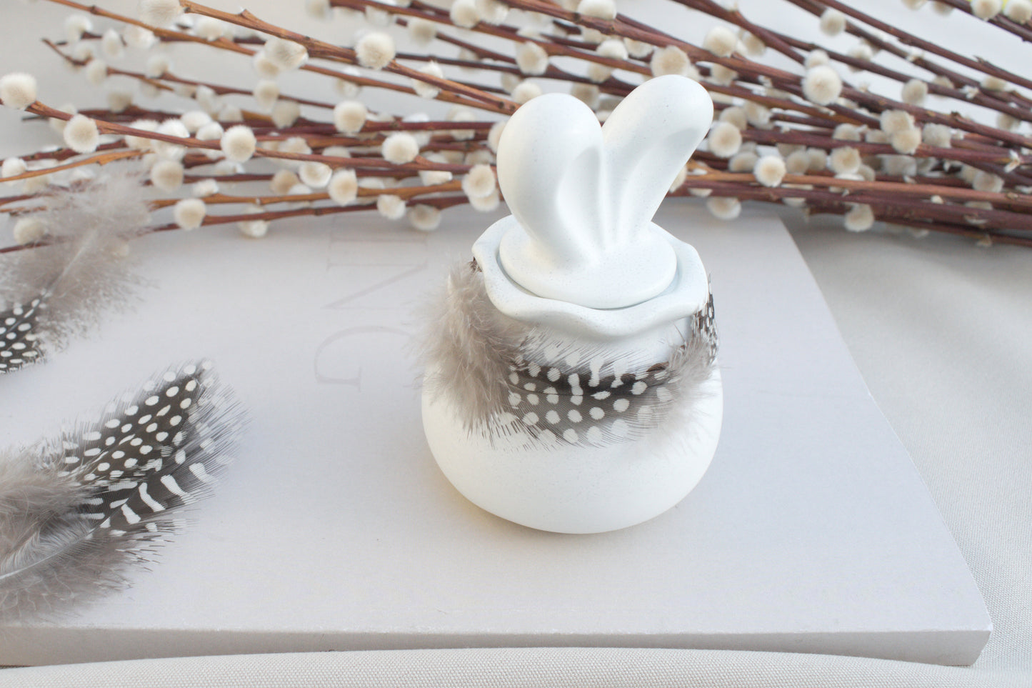 Osterdeko Skandi – Dose aus weißem Beton mit Hasenohren & Perlhuhn-Federn
