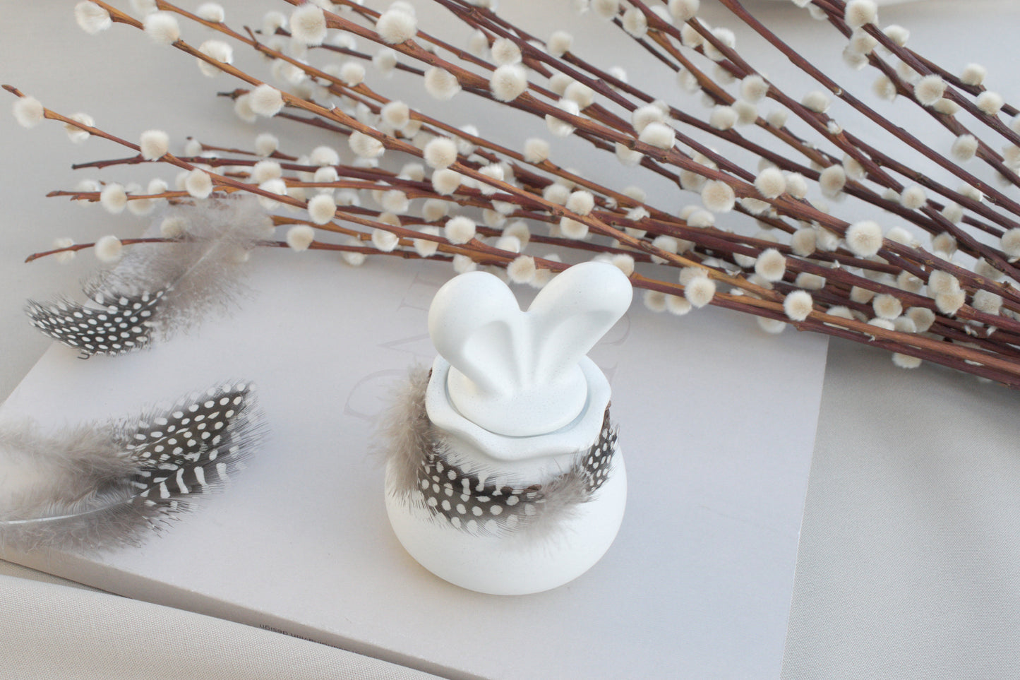 Osterdeko Skandi – Dose aus weißem Beton mit Hasenohren & Perlhuhn-Federn