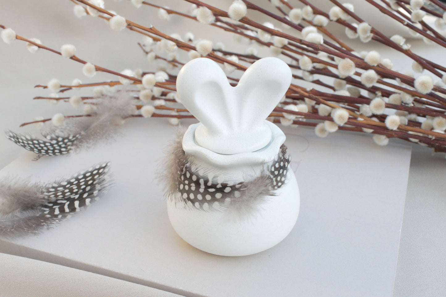 Osterdeko Skandi – Dose aus weißem Beton mit Hasenohren & Perlhuhn-Federn