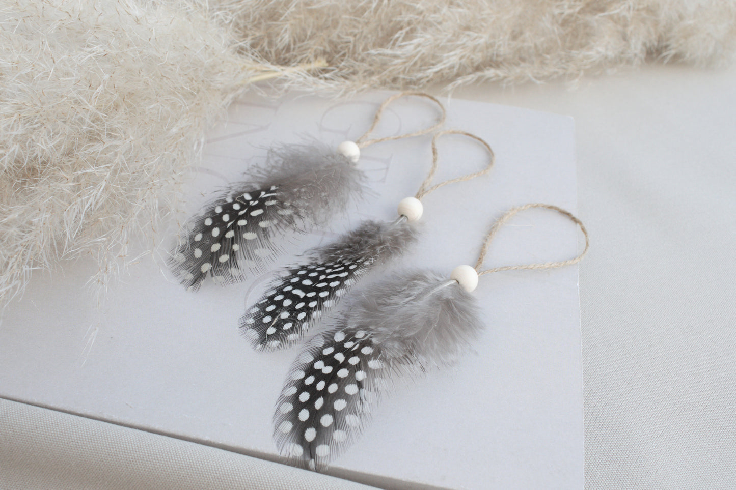 Osterdeko Anhänger Set aus gepunkteten Perlhuhn-Federn mit Naturholzperle