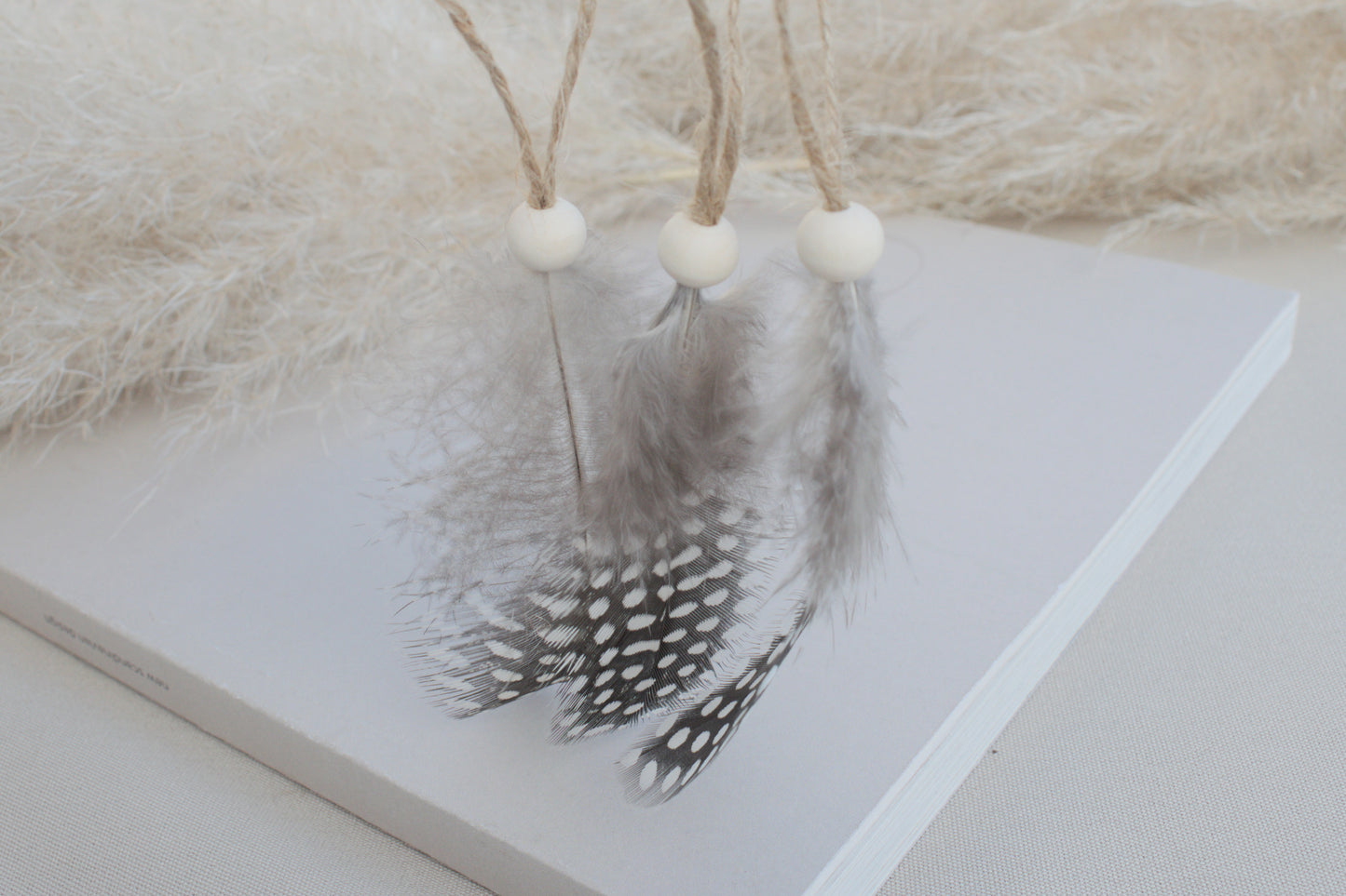 Osterdeko Anhänger Set aus gepunkteten Perlhuhn-Federn mit Naturholzperle