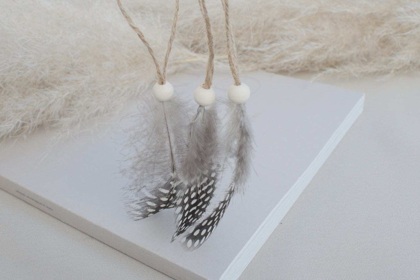 Osterdeko Anhänger Set aus gepunkteten Perlhuhn-Federn mit Naturholzperle
