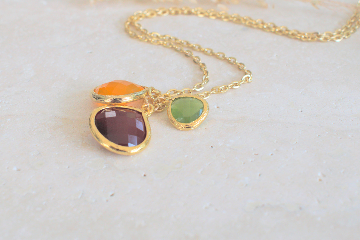 Goldene Kette mit bunten Steinen in verschiedenen Längen grün, orange und schwedenrot