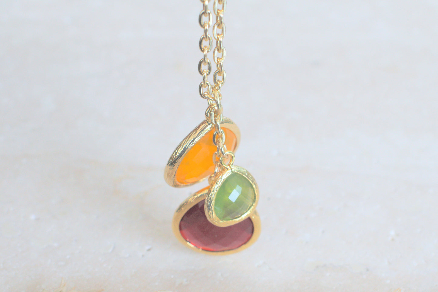 Goldene Kette mit bunten Steinen in verschiedenen Längen grün, orange und schwedenrot