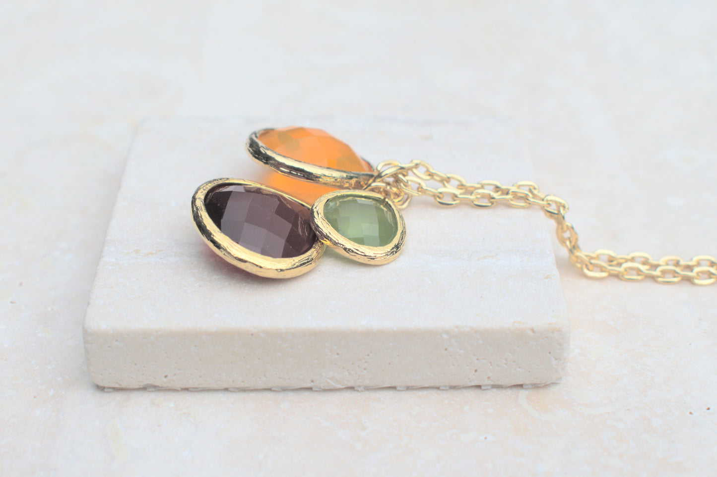 Goldene Kette mit bunten Steinen in verschiedenen Längen grün, orange und schwedenrot