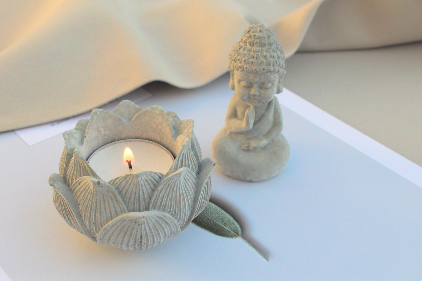 Kleiner Buddha mit Lotusblüte aus grauem Beton für Ruhe beim Yoga