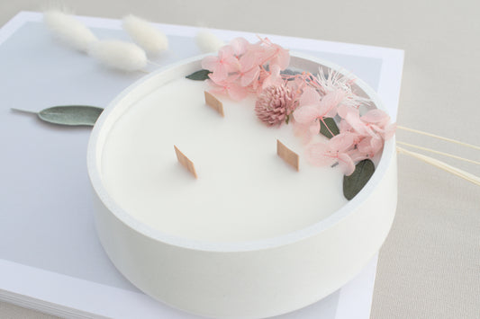 Handgemachte Kerze mit getrockneten Blüten im Betongefäß und Holzdocht, skandinavische Deko und Geschenkidee