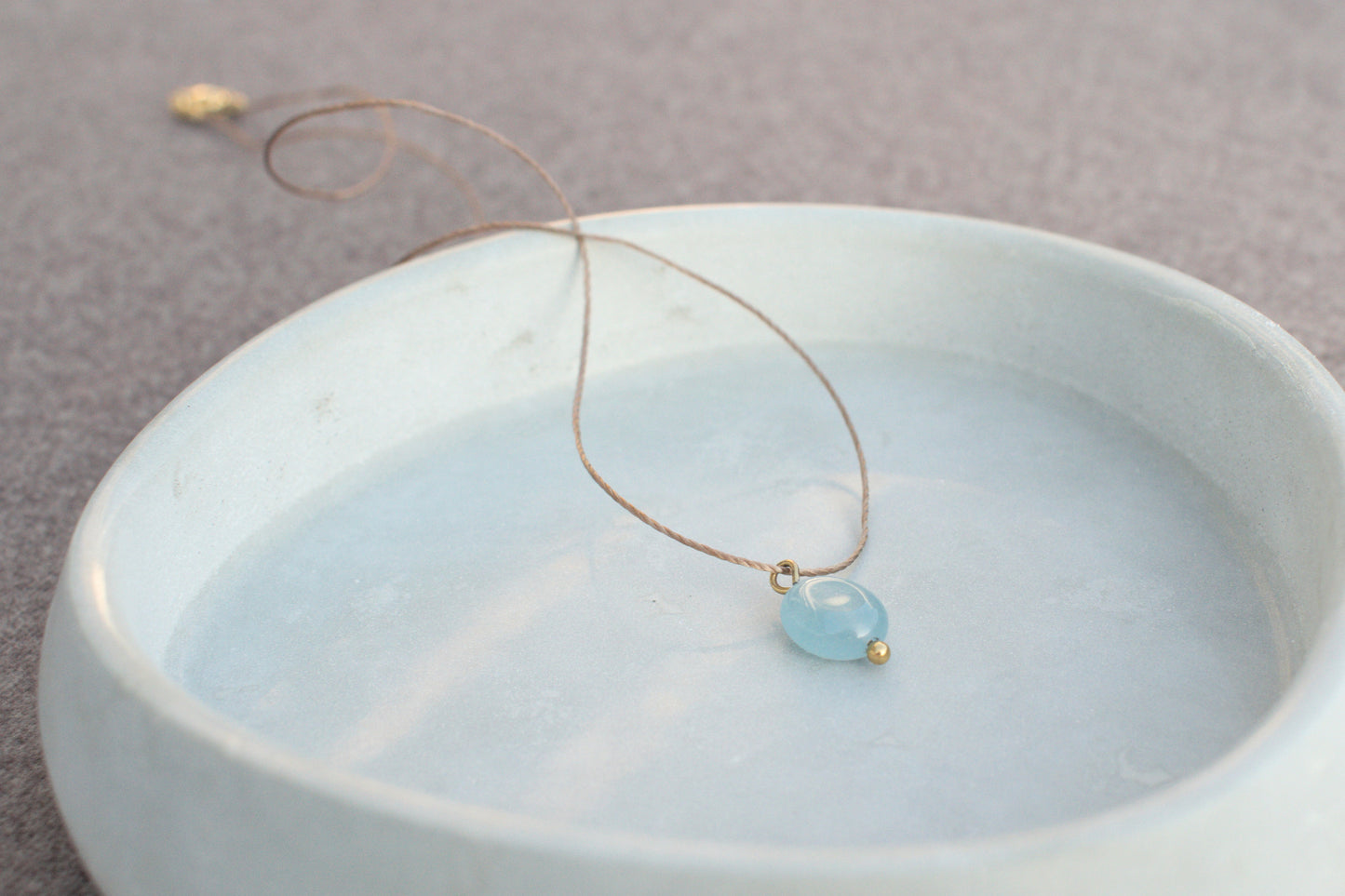 Minimalistische Halskette mit blauem, flachen Edelstein Aquamarin am braunen Nylonband